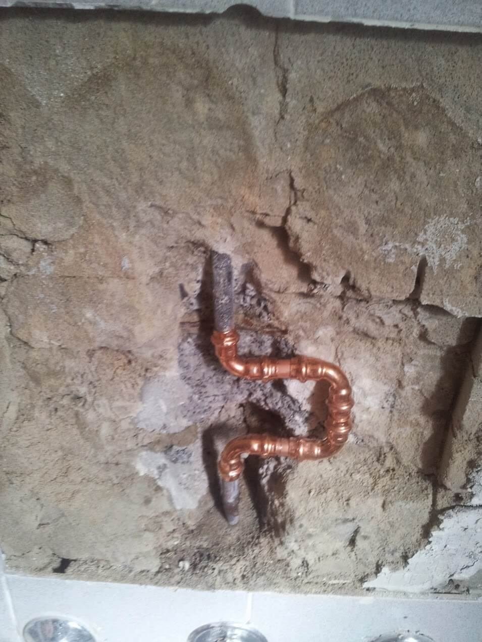 Copper pipe repair completed in a brick wall after a burst
