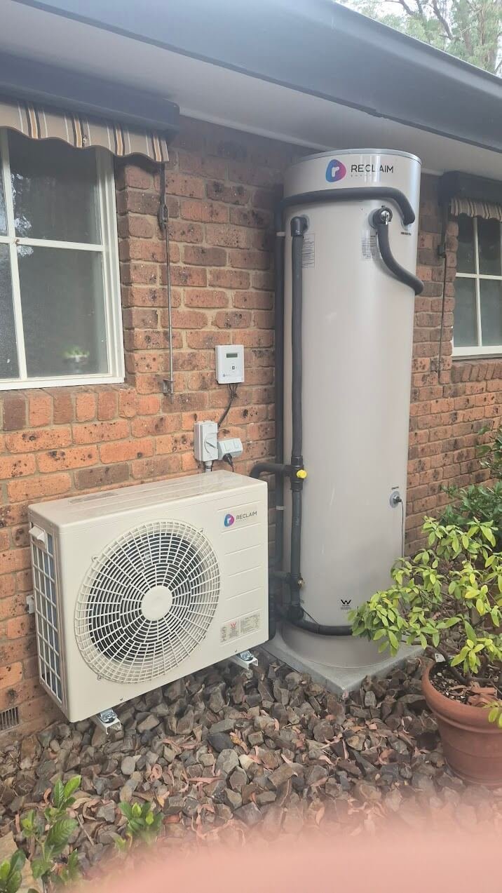 Heat pump hot water system installed on a brick home